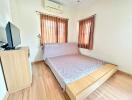 Cozy bedroom with wooden flooring, natural light, and air conditioning