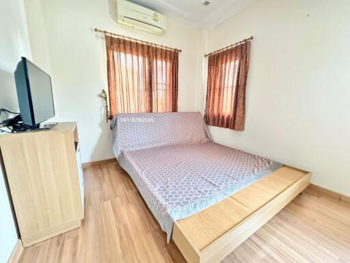 Cozy bedroom with wooden flooring, natural light, and air conditioning