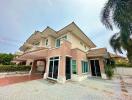 Spacious two-story residential house with a large driveway and tropical landscaping