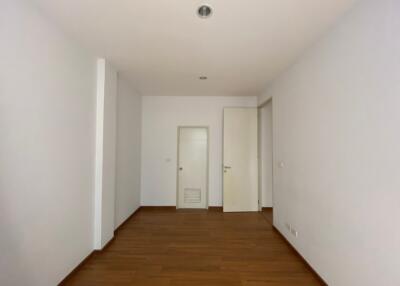 Bright and empty corridor with wooden flooring leading to rooms with white doors
