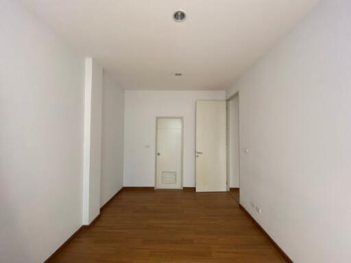 Bright and empty corridor with wooden flooring leading to rooms with white doors