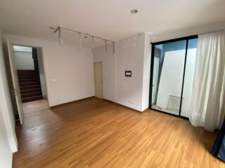 Spacious empty room with hardwood flooring, large windows and a glass door leading to an outdoor area