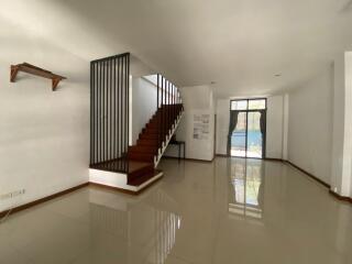 Bright and spacious living area with staircase and glossy floor