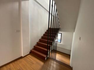 Wooden staircase with vertical metal balusters in a well-lit space