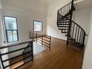 Bright staircase area with wooden floors and a black spiral staircase