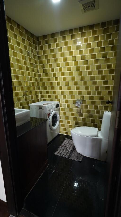 Small bathroom with yellow tile walls, modern fixtures, and washing machine