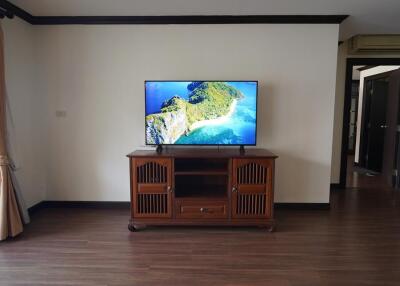 Spacious living room with large flat-screen TV and wooden flooring