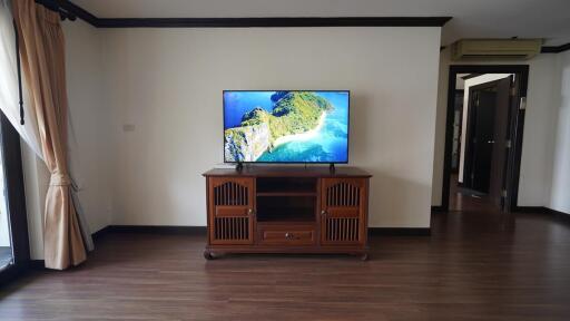 Spacious living room with large flat-screen TV and wooden flooring