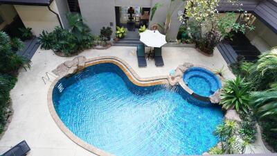 Elevated view of a lavish outdoor pool area with surrounding greenery