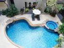 Elevated view of a lavish outdoor pool area with surrounding greenery