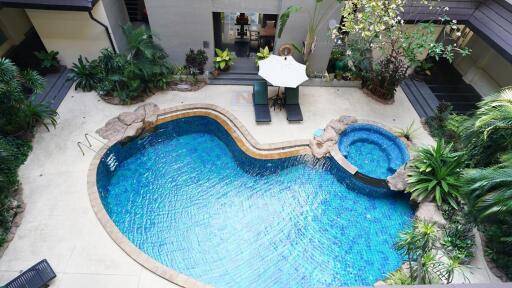 Elevated view of a lavish outdoor pool area with surrounding greenery