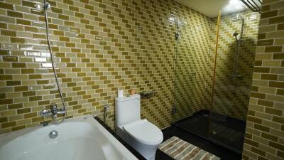 Modern bathroom with golden tiles, bathtub, and glass-enclosed shower