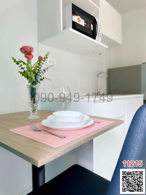Modern compact kitchen with microwave, dining area, and fresh flowers