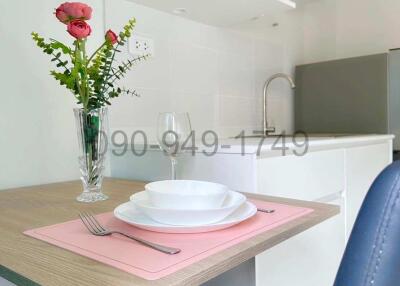 Modern compact kitchen with microwave, dining area, and fresh flowers
