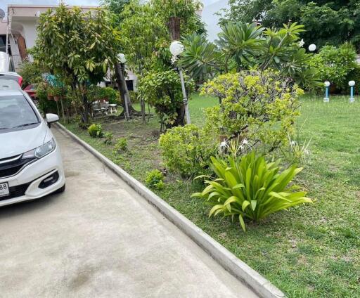 Spacious driveway with a well-maintained garden and car parked