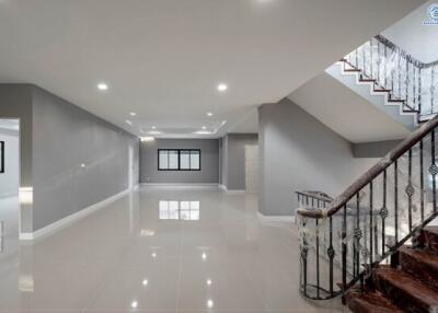 Spacious modern building interior with a glossy tiled floor, elegant staircase, and well-lit ceiling