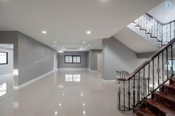 Spacious modern building interior with a glossy tiled floor, elegant staircase, and well-lit ceiling