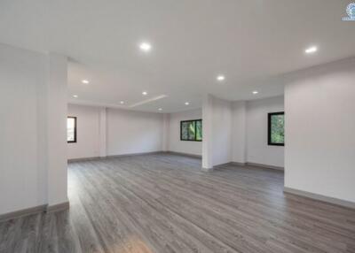 Spacious empty living room with hardwood flooring and recessed lighting
