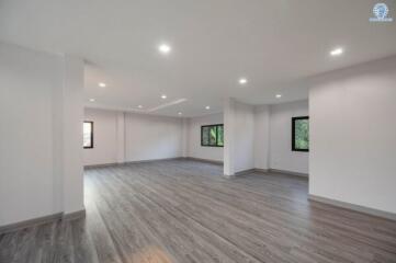 Spacious empty living room with hardwood flooring and recessed lighting