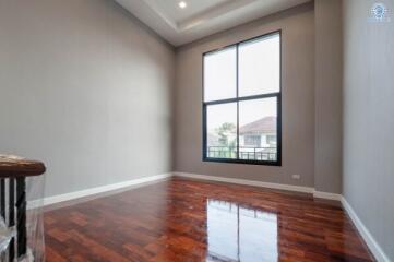 Spacious bedroom with large window and glossy hardwood floor