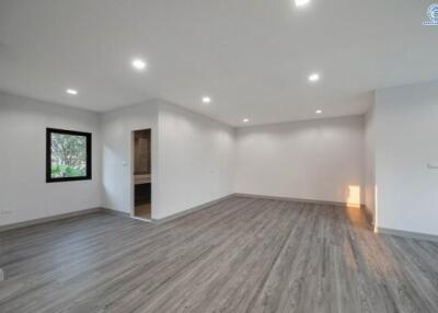 Spacious unfurnished bedroom with hardwood floors and modern lighting