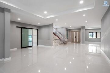 Spacious and bright modern living room with staircase and glossy tiled floor