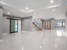 Spacious and bright modern living room with staircase and glossy tiled floor