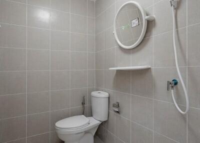 Modern white tiled bathroom with shower head and toilet