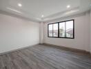 Spacious unfurnished bedroom with large window and hardwood floors