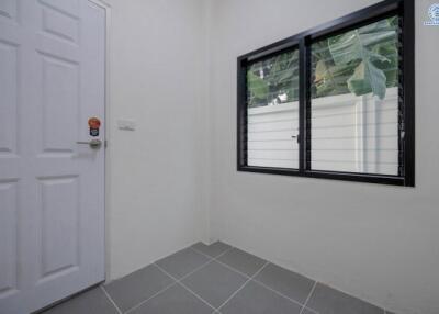 Bright empty room with tiled floor, large window, and white door