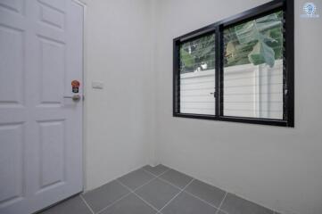 Bright empty room with tiled floor, large window, and white door