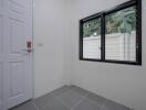 Bright empty room with tiled floor, large window, and white door