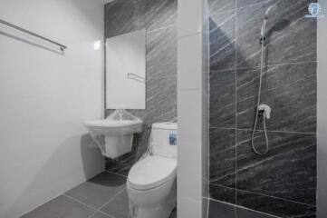 Modern bathroom with wall-mounted toilet, pedestal sink, and shower