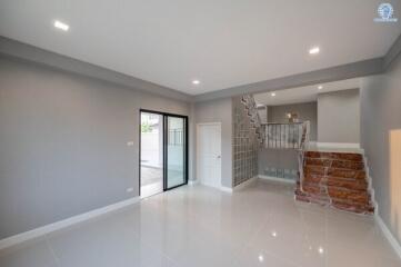 Modern living space with a glossy tiled floor, glass staircase, and an abundance of natural light