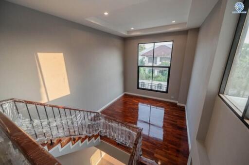 Spacious upper floor area of a building with polished hardwood flooring and natural lighting