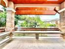 Spacious covered patio with wooden ceiling and stone pillars