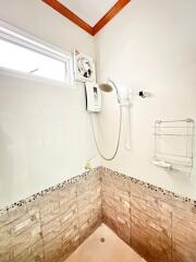 Compact bathroom with wall-mounted water heater and handheld shower