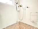 Compact bathroom with wall-mounted water heater and handheld shower
