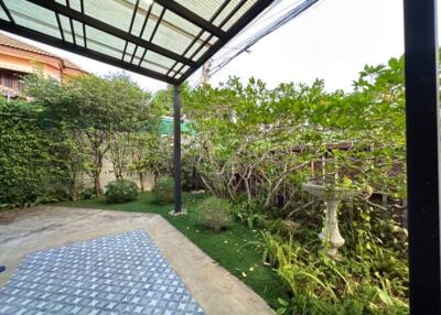 Spacious patio with a roof extension and surrounded by greenery