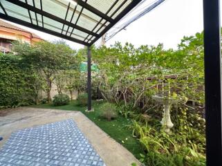 Spacious patio with a roof extension and surrounded by greenery