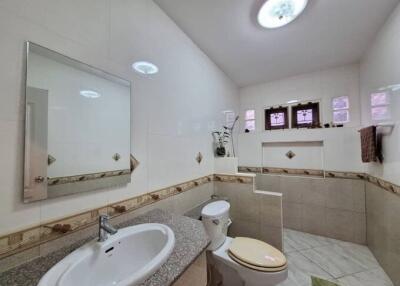 Modern bathroom with tiled walls, sink, and toilet