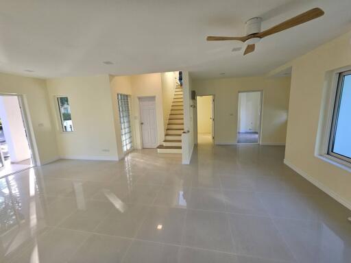 Spacious and well-lit living room with stairs and glossy tiled floor