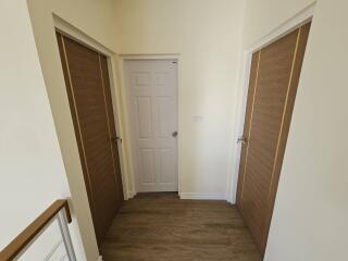 Bright corridor with white door and wooden floors