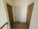 Bright corridor with white door and wooden floors