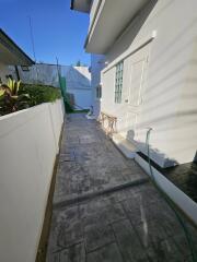 Paved side yard with outdoor seating and green hose