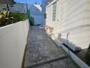 Paved side yard with outdoor seating and green hose