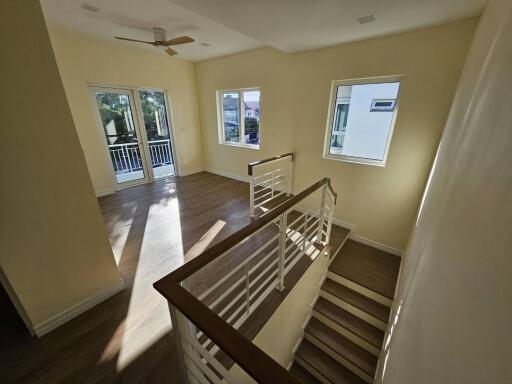 Spacious well-lit interior with staircase leading to lower level and doors to balcony