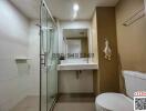 Modern bathroom interior with glass shower, white basin, and toilet