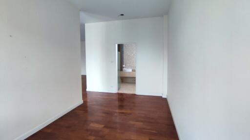 Spacious bedroom with hardwood floor and a view into the en-suite bathroom