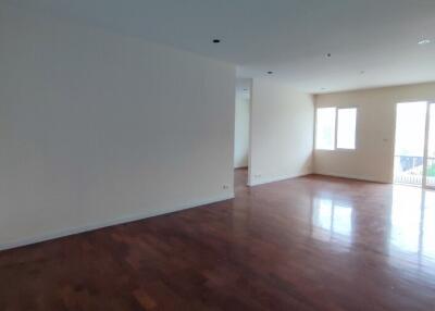 Spacious and well-lit empty living room with hardwood floors and balcony access